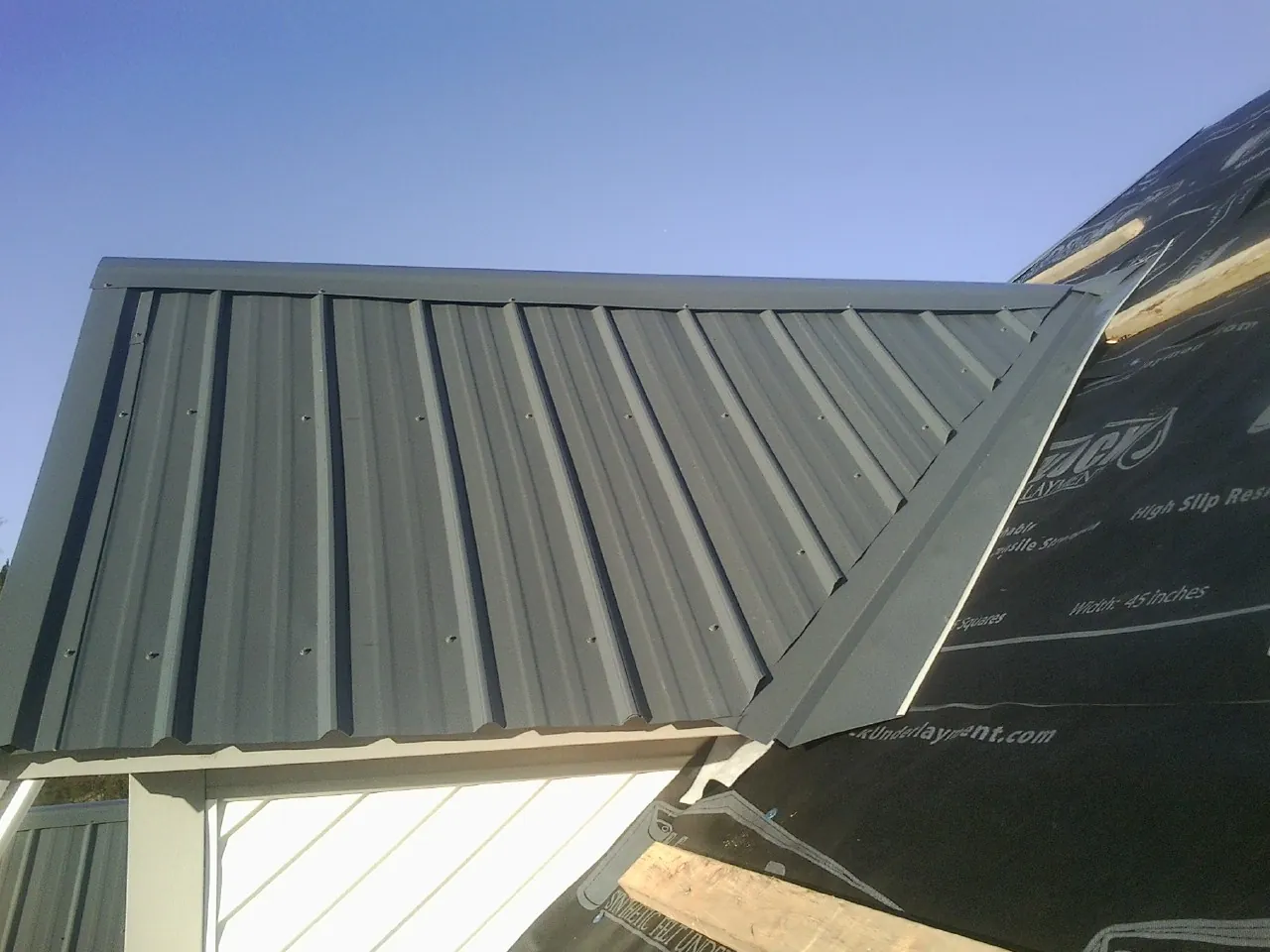 Gray metal roof panels going on over a garage gable in Coalville