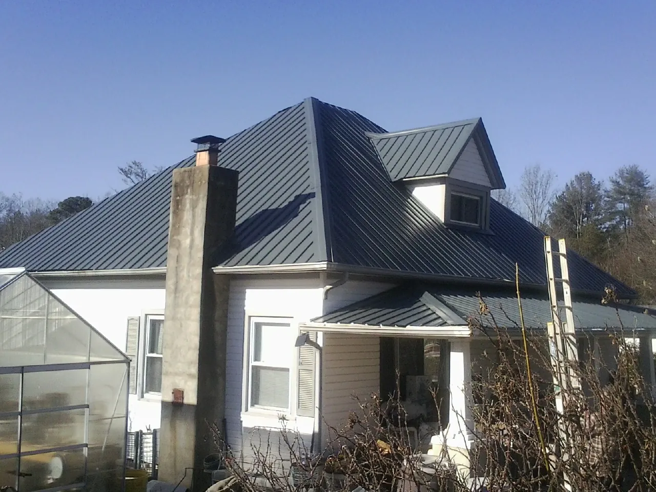 Dark blue standing seam metal roof on a white farmhouse with dormer — Slate & Tile Roof Repair by Roofing Brothers in Coalville