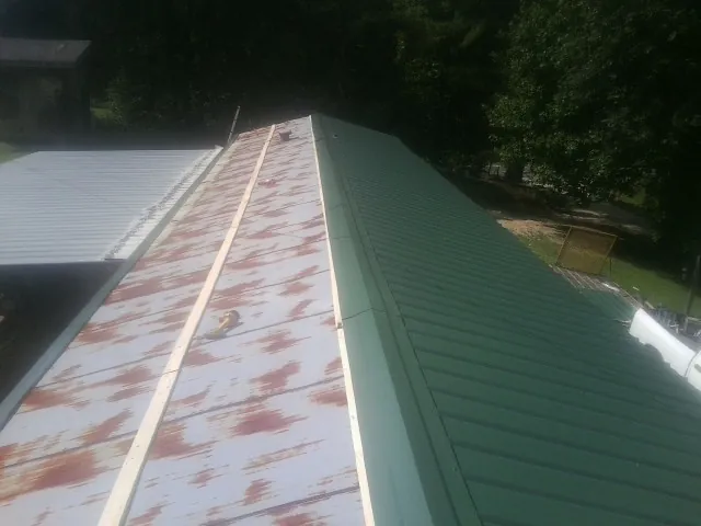 Old rusted panels beside newly installed green metal roofing — Wind Damage Roof Repair by Roofing Brothers in Coalville