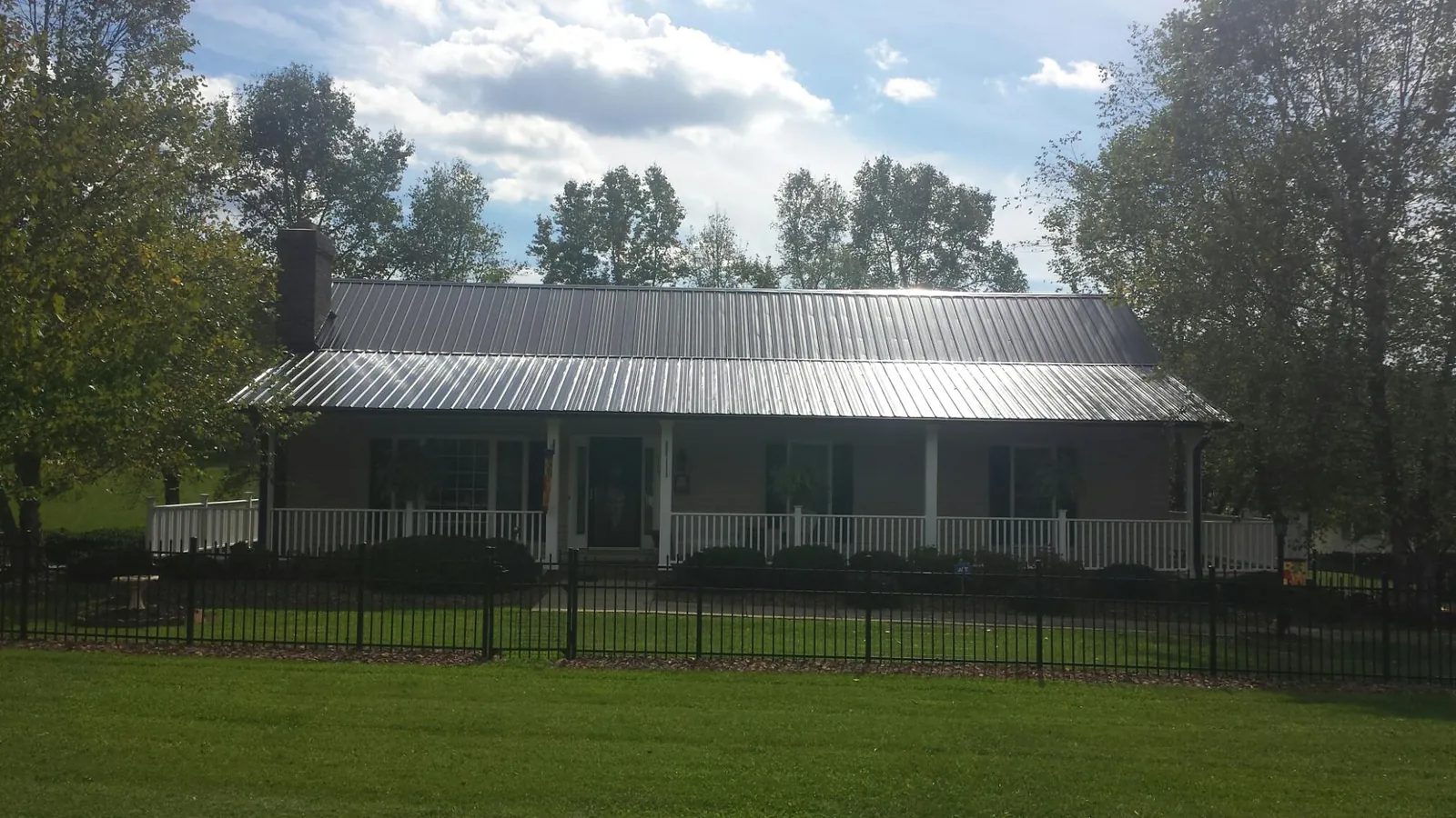 Gray metal roof on a brick ranch with a full width front porch — Gutter Guard Installation work by our crew in Coalville