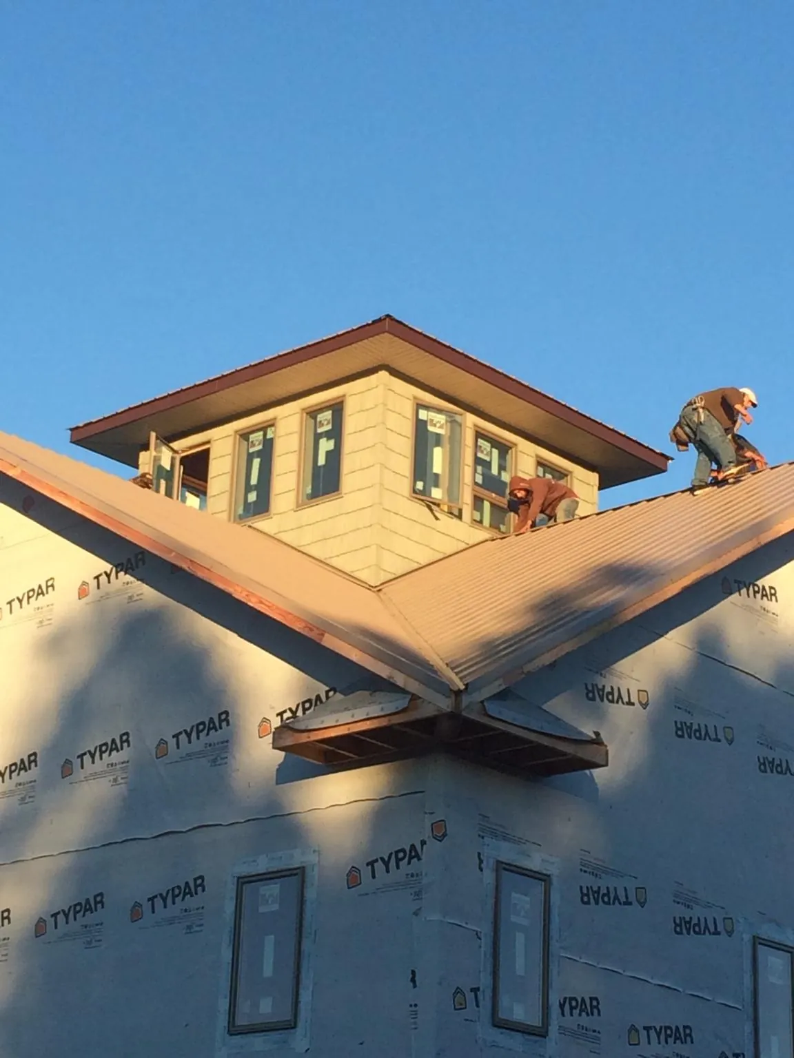 Roofers working around a rooftop cupola on a new metal roof at sunset — Roof Waterproofing in Coalville by Roofing Brothers
